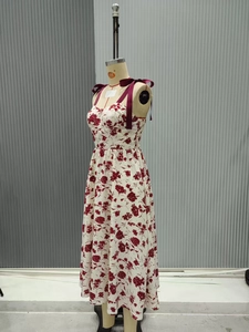 Détail des bretelles en satin bordeaux nouées en nœuds sur une robe fleurie chic