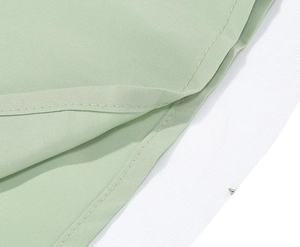Macro shot of mint green dress fabric showing fine plain weave and precise hem stitching