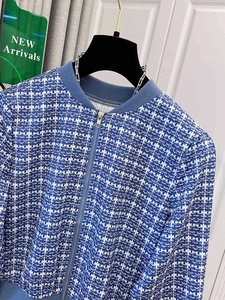 Detailed view of blue and white plaid tweed jacket with metal zipper and ribbed collar