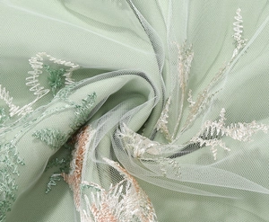 Detailed close-up of intricate floral embroidery on light green mesh lace fabric