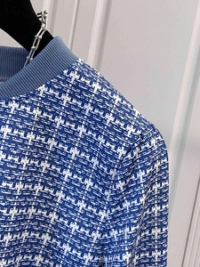 Detail of blue and white plaid tweed jacket showing textured weave and navy ribbed collar