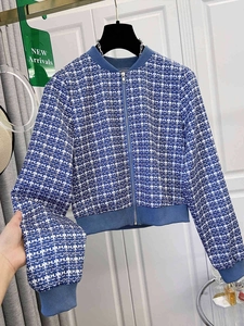 Detailed view of blue and white plaid tweed jacket with silver zipper and ribbed cuffs