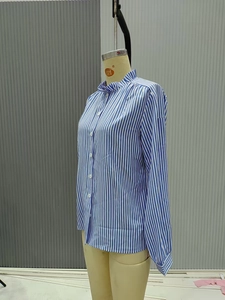 Detail of the blue and white striped shirt featuring ruffled stand collar and buttons