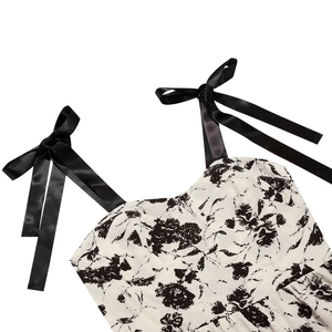 Détail d'une robe fleurie avec bretelles en satin noir nouées et tissu imprimé doux