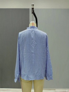 Detail of ruffled stand collar and blue vertical stripes on long sleeve shirt