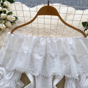 Top bianco con spalle scoperte, maniche a sbuffo, pizzo ricamato e volant a balze