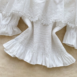 Camicia bianca a spalle scoperte con ricami in pizzo, maniche a sbuffo e vita smaltata