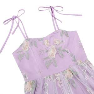 Close-up of pink floral embroidery and adjustable bow straps on purple dress