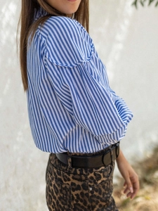 Detail of blue striped shirt showing ruffled shoulder design and vertical fabric texture