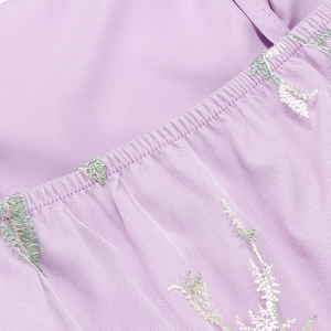Detailed close-up of purple embroidery on sheer mesh fabric with elastic stitching