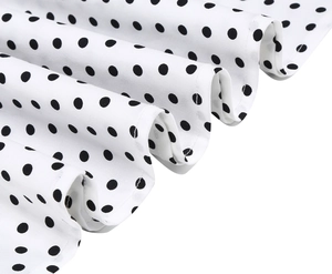 Gros plan d'un tissu blanc à pois noirs montrant le drapé rétro et la texture fine