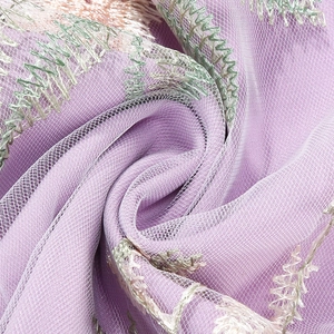 Macro detail of purple tulle fabric with delicate wave embroidery and fine mesh texture