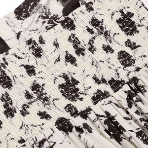 Détail du tissu smocké élastique avec imprimé floral noir et blanc et rubans noirs