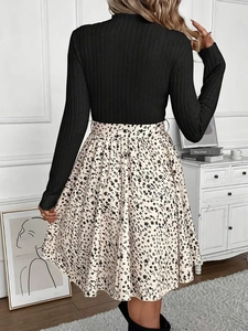 Detail view of the back of a black knitted long sleeve top and beige floral A-line skirt