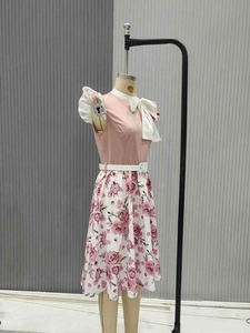 Detail of pink vintage dress with floral skirt, white bow tie collar and waist belt
