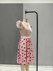 Detail of pink strawberry print dress with white Peter Pan collar and bow on mannequin