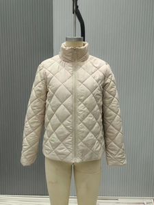 Detail of beige diamond quilted jacket with stand collar and zipper on a mannequin