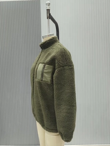 Close-up of olive green sherpa fleece jacket featuring high collar and contrast chest pocket