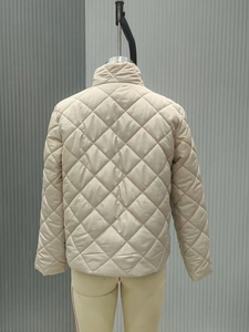 Detail of beige diamond quilted jacket showing the textured waterproof fabric and high collar