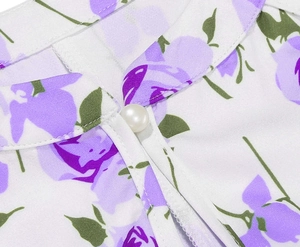 Detailansicht des Ausschnitts eines weißen Blumenkleides mit elegantem Perlenknopf-Akzent