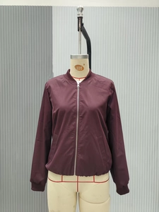 Detail of burgundy bomber jacket featuring silver metal zipper and ribbed knit trims