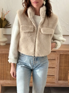Detail of soft beige faux fur vest featuring stand collar and metal zipper closure