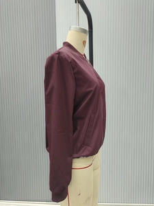 Close-up of a burgundy bomber jacket with ribbed collar and smooth metallic zipper