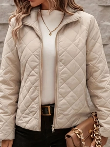 Close-up of the elegant beige diamond-quilted jacket with a smooth metal zipper detail