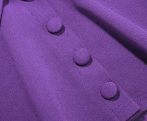 Dettaglio del tessuto viola con tre bottoni rivestiti in stoffa e finitura crespa ruvida
