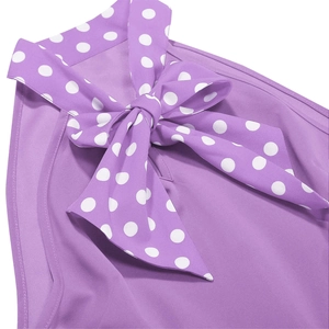 Detail of a purple sleeveless vintage dress featuring a large white polka dot bow tie