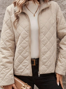 Detail of beige diamond-quilted jacket with metal zipper and elegant stand collar