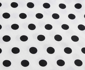 Close-up detail of high-quality white fabric with black polka dots on vintage dress