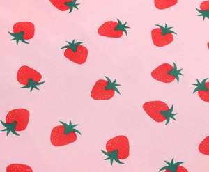 Detail of light pink fabric featuring vibrant red strawberry patterns and green leaves