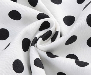 Close-up of black and white polka dot fabric with twill texture and soft drape detail