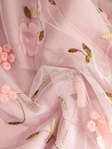Detail of pink mesh fabric with gold embroidery and 3D floral appliques on long skirt