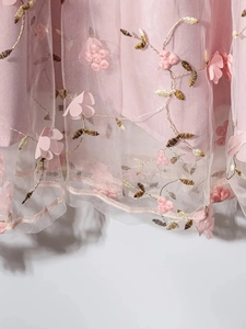 Detail view of 3D floral appliques and vine embroidery on pink layered tulle skirt