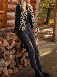 Detailed view of leopard print fleece vest paired with dark denim jeans in an autumn setting