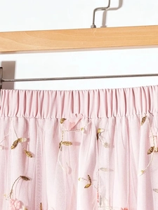 Detail of pink mesh skirt featuring intricate gold leaf embroidery and 3D floral accents