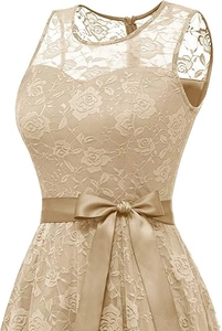 Détail de la robe en dentelle dorée avec ceinture en ruban satiné et décolleté élégant en dentelle