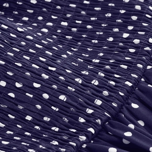 Detail of navy blue polka dot fabric showing elastic smocking texture and pleats