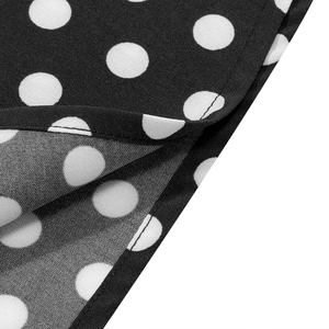 Detailed close-up of white polka dot pattern on black fabric with fine hem stitching