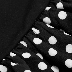 Detailed view of polka dot pattern and pleated stitching on a black vintage dress