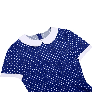 Detail of navy blue polka dot dress featuring a white Peter Pan collar and back zipper