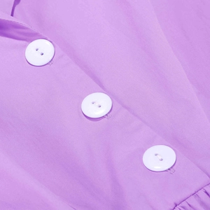 Détail de la robe violette montrant les boutons blancs et la texture plissée du tissu