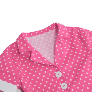 Detail of pink polka dot girls' dress featuring a lapel collar and large white buttons