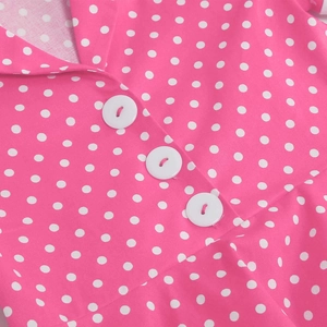 Detail of girls' retro pink polka dot dress showing V-neckline and white buttons