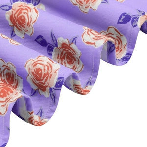 Close-up of purple floral dress fabric with orange roses and ruffle edge detail