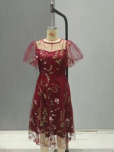 Detail of burgundy mesh dress with intricate floral embroidery and puff sheer sleeves