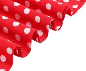 Close-up detail of red polka dot dress fabric with retro pleated hem and smooth texture