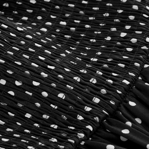 Macro detail of smocking elastic structure on black and white polka dot fabric
